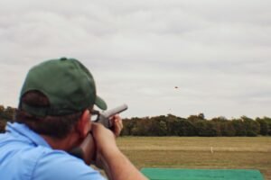 A dynamic image of a shooter firing at a clay target in a Super Sporting competition